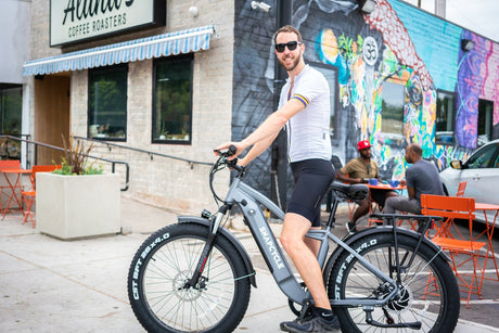 Rider on a Snapcycle e-bike commuting past a city street mural