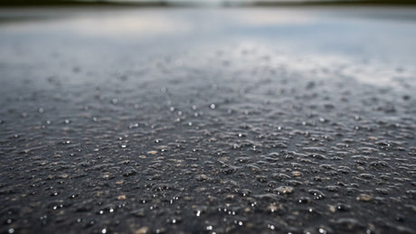Wet asphalt road surface with rain droplets on an overcast day