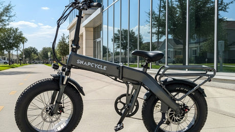 Snapcycle e-bike on a sunny city bike path beside a modern glass building